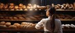 attractive female baker between shelves looking and checking freshly baked bread very carefully bakery industry. Copy space image. Place for adding text or design