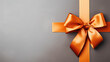 A vibrant Orange gift ribbon with a bow against a gray background