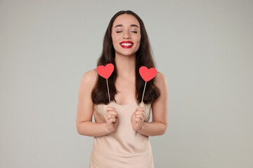 Poster - Beautiful young woman with paper hearts on grey background