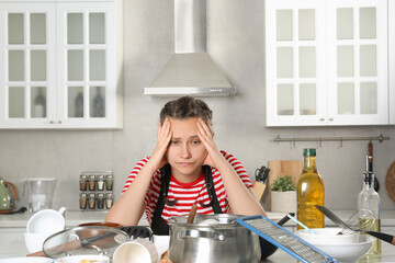 Canvas Print - Upset woman in messy kitchen. Many dirty dishware and utensils on table