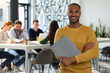 © New Africa - Team of employees working together in office. Happy man with folder indoors, space for text