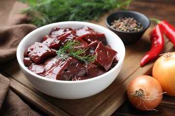 Canvas Print - Cut raw beef liver with onions, spices, chili peppers and dill on wooden table