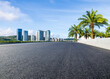 © ABCDstock - Asphalt road and city buildings with green palm tree under blue sky