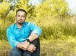 © bogdan vacarciuc - A man in the woods on a beautiful autumn day. He sits in the grass and contemplates the landscape.