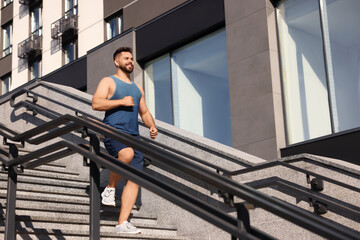 Poster - Happy man running down stairs outdoors on sunny day, low angle view. Space for text