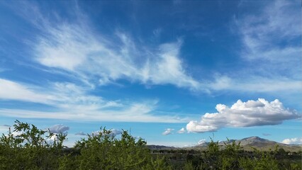 Wall Mural - Peaceful landscape featuring a blue sky with white clouds above a distant mountain