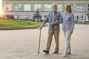 Poster - Senior man with walking cane and mature woman outdoors. Space for text