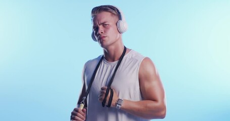 Wall Mural - Man, serious face and headphones with skipping rope for fitness, exercise and training in studio. Confidence, person and athlete with music, audio and song for workout and sport with blue background