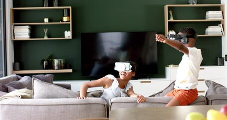 Wall Mural - happy african american brother and sister in vr headsets on sofa, copy space, slow motion