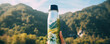© Michal - Reusable thermos in hand against forest mountains. thermo water bottle in hiking time.