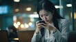 Young busy stressed upset Asian business woman holding cellphone using mobile phone, looking at smartphone feeling tired frustrated reading bad news on financial market working in office