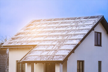 Wall Mural - Solar Panel Roof House with Melted Snow. Snow Covered Rooftop with Solar Panels in Snowy Winter with Sun light.