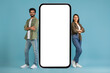 © Prostock-studio - Positive young indian couple standing by big cell phone, mockup