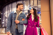 Young European couple enjoys festive winter shopping spree outside mall