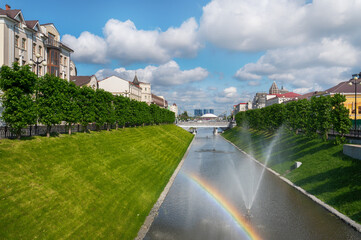 Wall Mural - Kazan, Russia, June 1, 2023: view of the Bulak water canal with rainbow, bridges and fountains in the city centre on a sunny summer day. View towards the Kazanka River