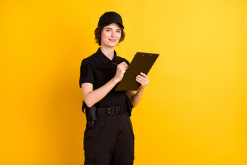 Sticker - Portrait of charming girl hands hold clipboard pen look camera smile isolated on yellow color background