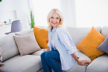 Sticker - Photo of beautiful mature aged optimistic business lady enjoying her perfect home design interior sitting soft divan with pillow indoors