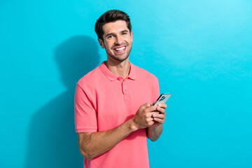 Photo of cheerful young boyfriend sending a date request to girlfriend in application using phone isolated on cyan color background