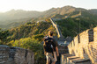 Joven viajero de espaldas en la muralla China al atardecer, en un paisaje montañoso