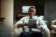 © Marko Geber - Smiling happy businessman using tablet in hotel lobby