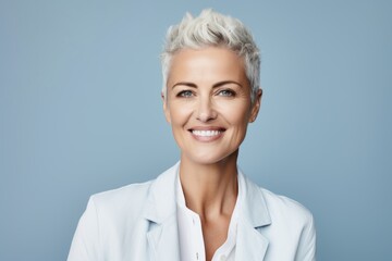 Wall Mural - Portrait of smiling businesswoman with short hair, over blue background