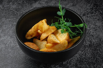 Wall Mural - Potato wedges roasted in the oven in a dark plate