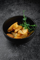 Wall Mural - Potato wedges roasted in the oven in a dark plate