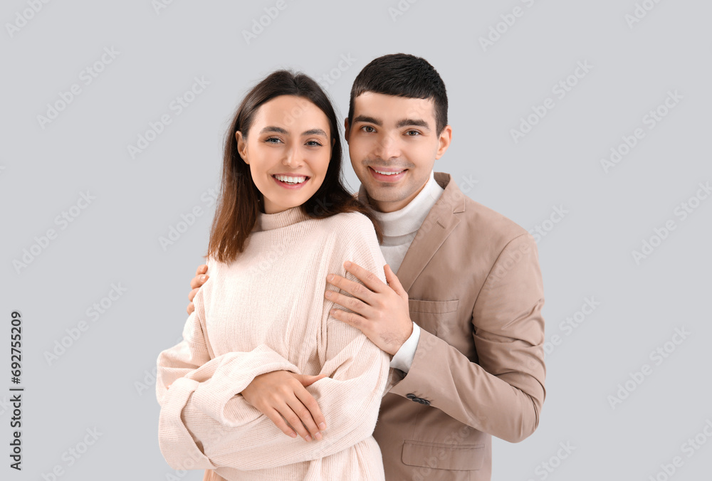 Lovely young couple hugging on light background