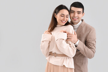 Wall Mural - Lovely young couple hugging on light background