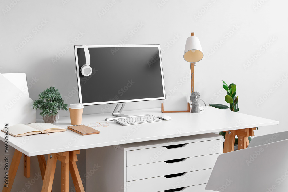 Comfortable workplace with modern computer near light wall