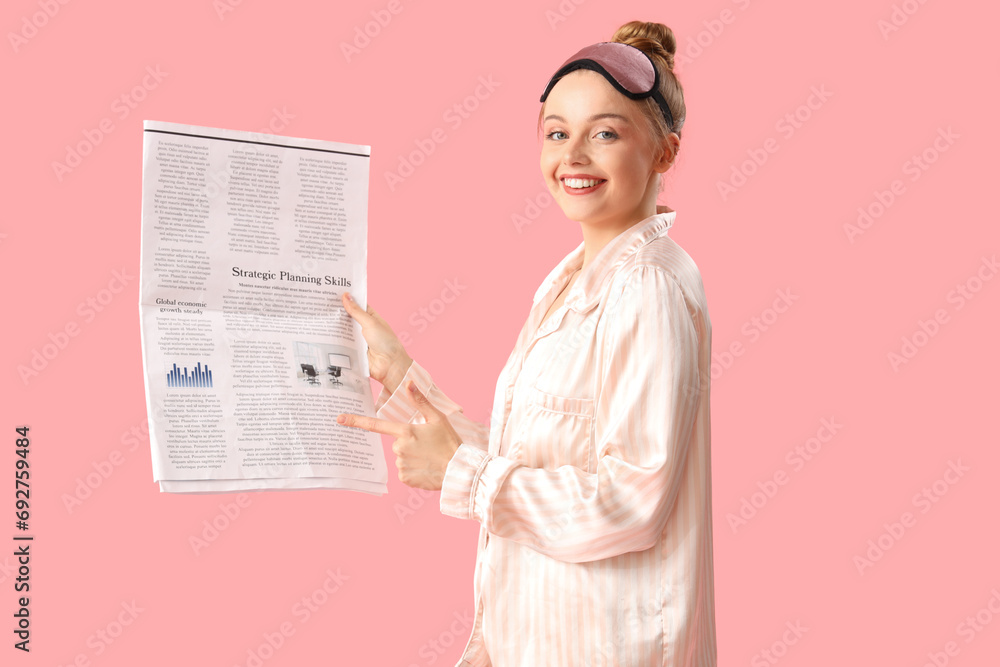 Young woman with newspaper on pink background