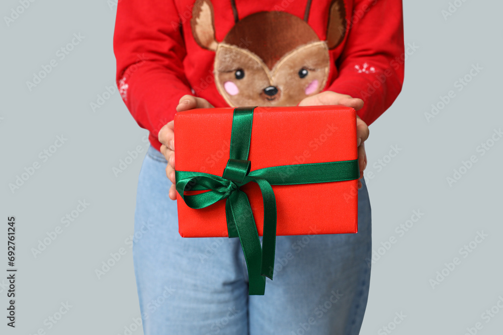 Woman with Christmas gift on grey background