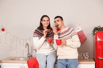 Sticker - Young couple drinking hot cocoa with cookies in kitchen on Christmas eve