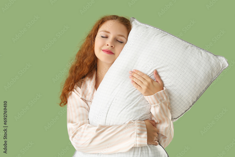 Beautiful young woman with white soft pillow on green background