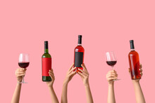 Female Hands With Bottles Of Wine And Glasses On Pink Background