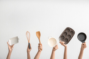 Wall Mural - Female hands with different kitchen utensils on light background