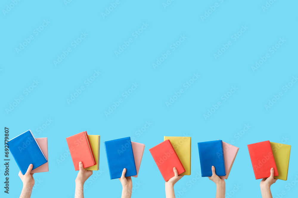 Hands holding books on blue background