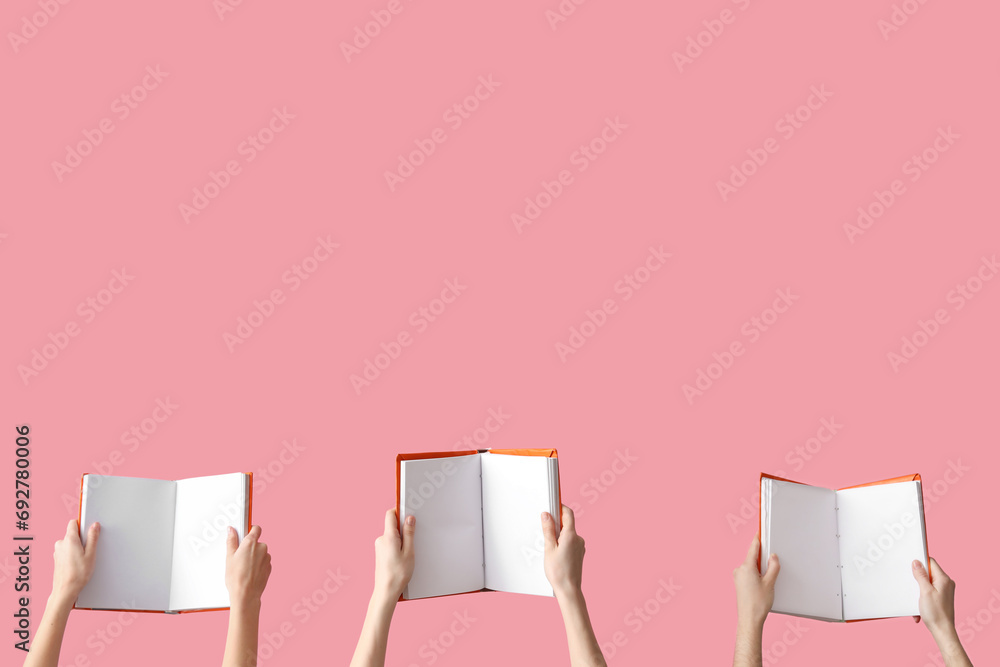 Hands holding open books on pink background