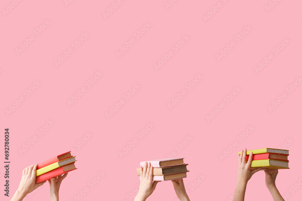 Hands holding books on pink background