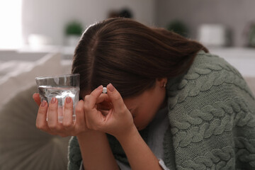 Wall Mural - Depressed woman with antidepressant pill and glass of water indoors
