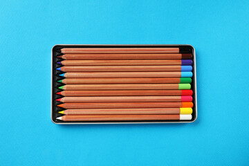 Wall Mural - Box with many colorful pastel pencils on light blue background, top view. Drawing supplies