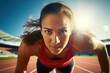 Young woman athlete at starting position ready to start a race. Female sprinter ready for sports exercise on racetrack with sun flare.