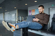 © Julija - portrait of cheerful man relaxing at airport with bag and mobile phone, guy waiting for flight using mobile phone communicating in social media, searching information online.