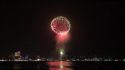 Wall Mural - Celebration. Skyline with fireworks light up sky over landmark skyscraper on the sea in Pattaya International Fireworks Festival, Thailand. Holidays, celebrating New year and tet holiday