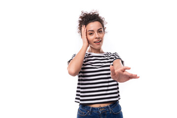 Wall Mural - young positive curly brunette woman in a striped casual t-shirt calls to her