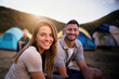 adult man and woman camping at campsite in nature, tent in background, joy and fun