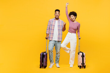 Wall Mural - Traveler happy couple two friend family man woman wearing casual clothes hold suitcase bag isolated on plain yellow background. Tourist travel abroad in free time rest getaway Air flight trip concept