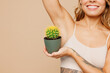 © ViDi Studio - Close up young nice lady woman with slim body perfect skin wear nude top bra lingerie stand raise up hand touch armpit hold cactus isolated on plain pastel beige background Lifestyle diet fit concept.