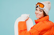 © ViDi Studio - Side back view close up young fun woman wear warm padded windbreaker jacket hat ski goggles mask hold snowboard travel rest spend weekend winter season in mountains isolated on plain blue background