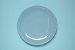 © New Africa - One ceramic plate on light blue background, top view